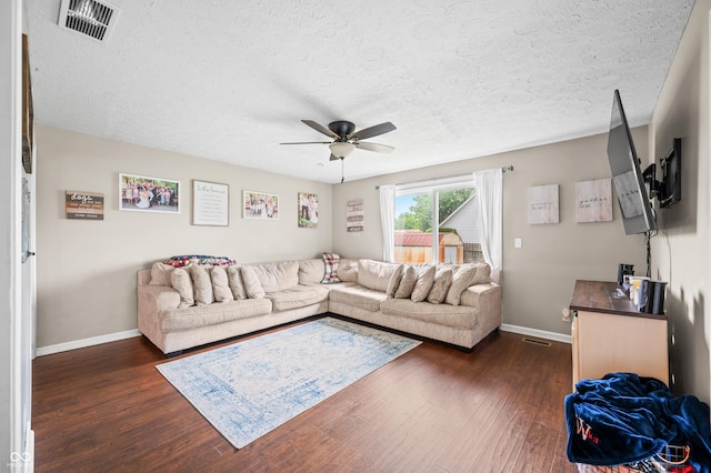 living area with a ceiling fan, baseboards, dark wood finished floors, and a textured ceiling