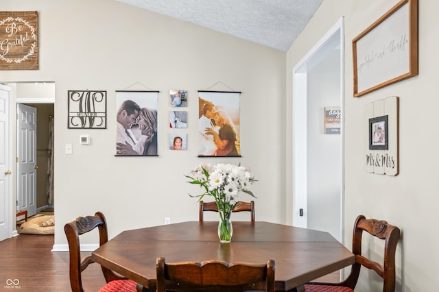 dining room with dark wood-style flooring, a textured ceiling, and baseboards