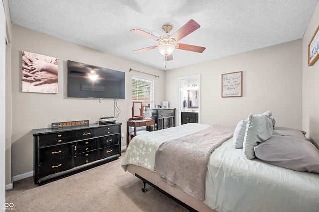 carpeted bedroom with a textured ceiling, ceiling fan, ensuite bathroom, and baseboards