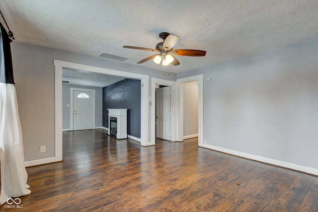 unfurnished living room featuring a ceiling fan, a textured ceiling, wood finished floors, baseboards, and a fireplace
