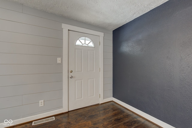 foyer entrance featuring dark wood-style flooring, baseboards, and a textured ceiling