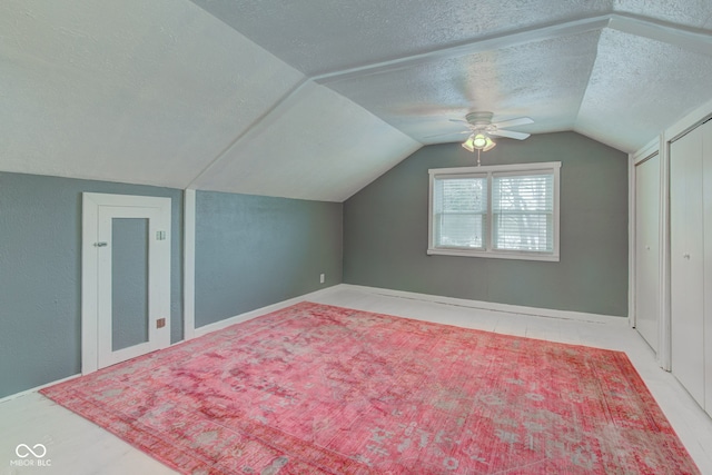 additional living space with lofted ceiling, ceiling fan, a textured ceiling, and baseboards