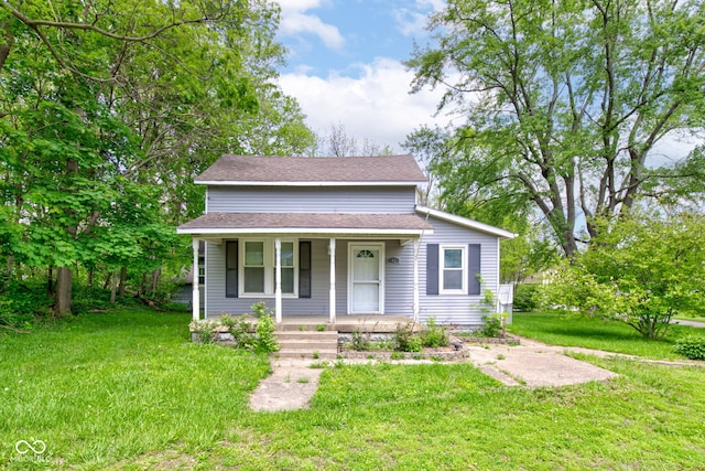 bungalow-style home with a porch, a front yard, and roof with shingles