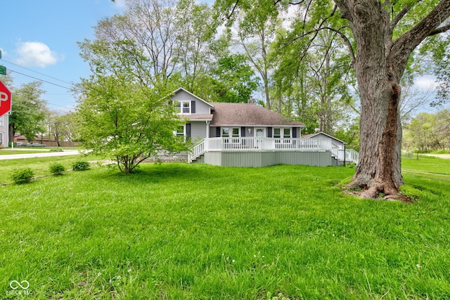view of front of property featuring a deck, a front yard, a chimney, and roof with shingles
