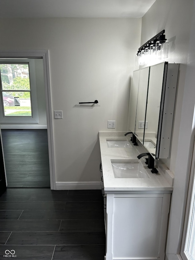 full bath featuring wood finished floors, baseboards, and double vanity