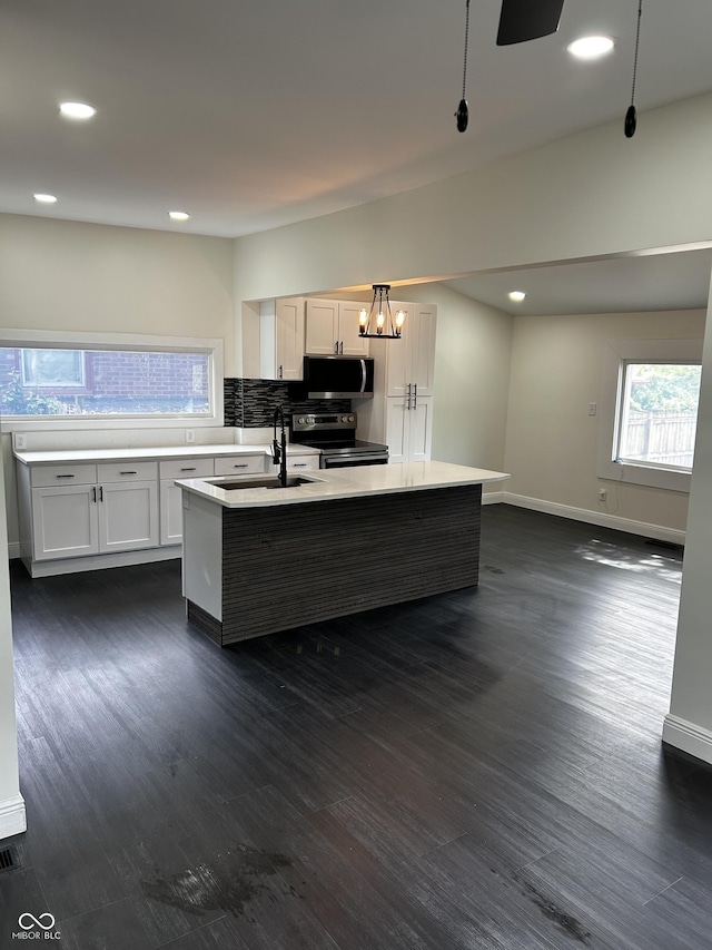 kitchen with dark wood-style floors, appliances with stainless steel finishes, a kitchen island with sink, light countertops, and recessed lighting