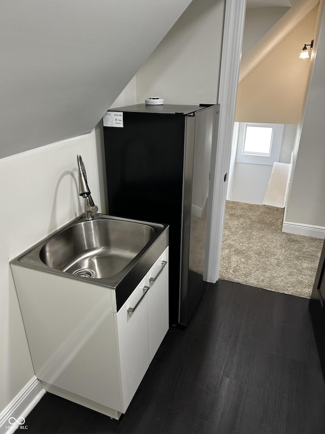 kitchen with white cabinetry, freestanding refrigerator, a sink, dark wood-type flooring, and vaulted ceiling
