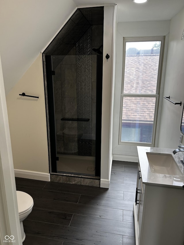 bathroom with wood finished floors, a stall shower, toilet, and baseboards