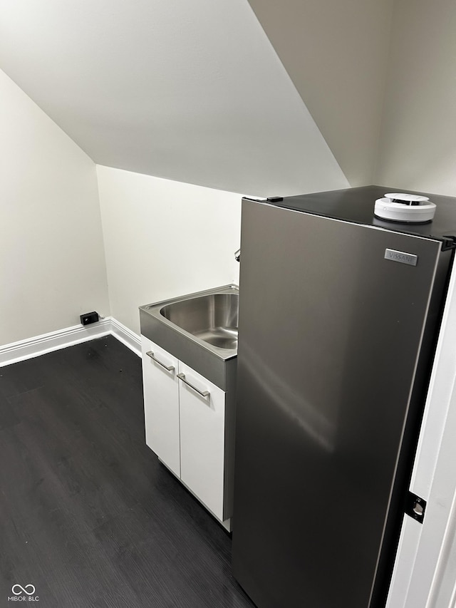 kitchen featuring freestanding refrigerator, dark wood-style floors, white cabinets, baseboards, and a sink