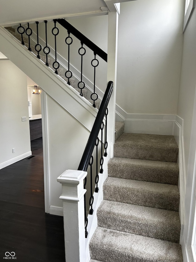 stairs featuring wood finished floors, baseboards, and a chandelier