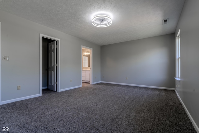 6491 Enclave Blvd, Greenwood, IN 46143 - unfurnished bedroom featuring dark carpet, a textured ceiling, baseboards, and connected bathroom
