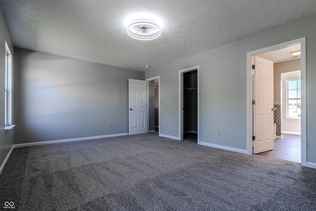 6491 Enclave Blvd, Greenwood, IN 46143 - unfurnished bedroom featuring a textured ceiling, carpet, baseboards, and a walk in closet