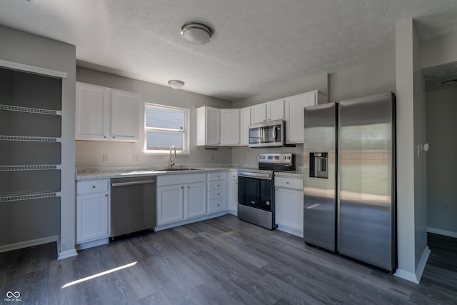 6491 Enclave Blvd, Greenwood, IN 46143 - kitchen featuring stainless steel appliances, a sink, white cabinetry, dark wood-style flooring, and a textured ceiling