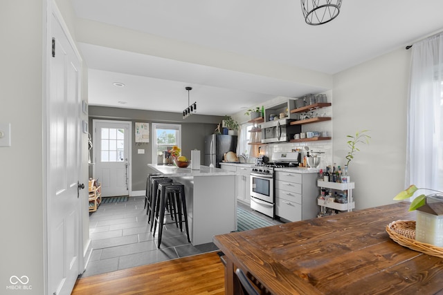 2336 Sycamore St, Columbus, IN 47201 - kitchen featuring appliances with stainless steel finishes, open shelves, a kitchen bar, dark wood-style floors, and a center island