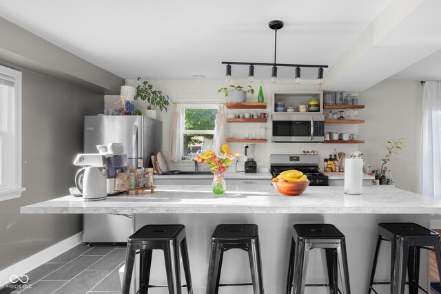 2336 Sycamore St, Columbus, IN 47201 - kitchen with appliances with stainless steel finishes, open shelves, light countertops, a kitchen breakfast bar, and tasteful backsplash