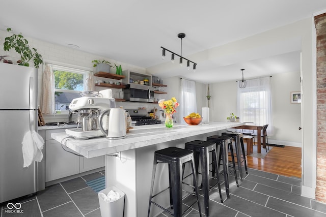 2336 Sycamore St, Columbus, IN 47201 - kitchen featuring appliances with stainless steel finishes, dark tile patterned floors, healthy amount of natural light, and a breakfast bar
