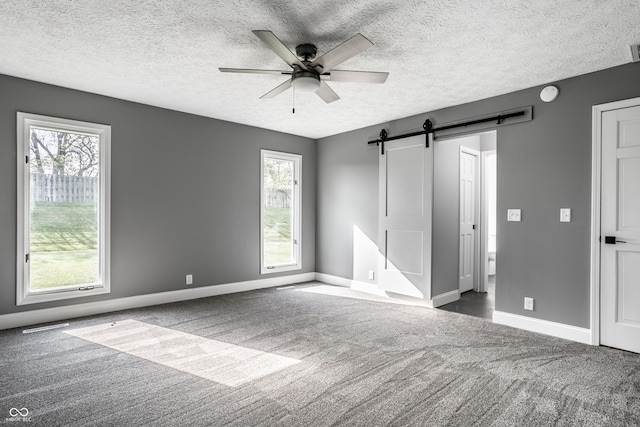 51 Glasgow Ln, Noblesville, IN 46060 - unfurnished bedroom featuring carpet floors, a barn door, baseboards, a textured ceiling, and a ceiling fan