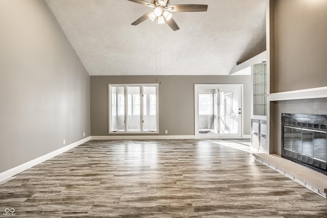 51 Glasgow Ln, Noblesville, IN 46060 - unfurnished living room with vaulted ceiling, a textured ceiling, a glass covered fireplace, a ceiling fan, and wood finished floors