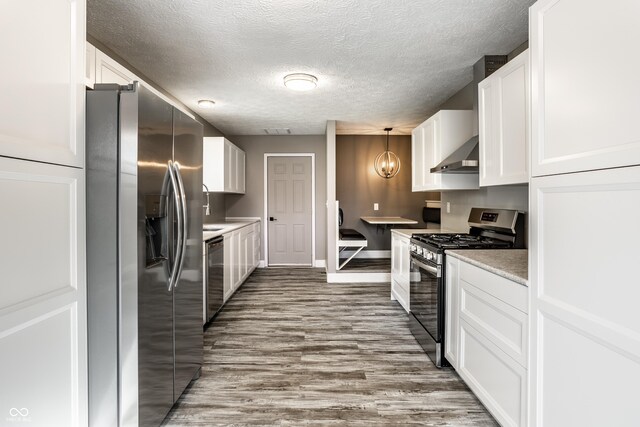 51 Glasgow Ln, Noblesville, IN 46060 - kitchen with stainless steel appliances, white cabinets, a textured ceiling, baseboards, and wall chimney exhaust hood