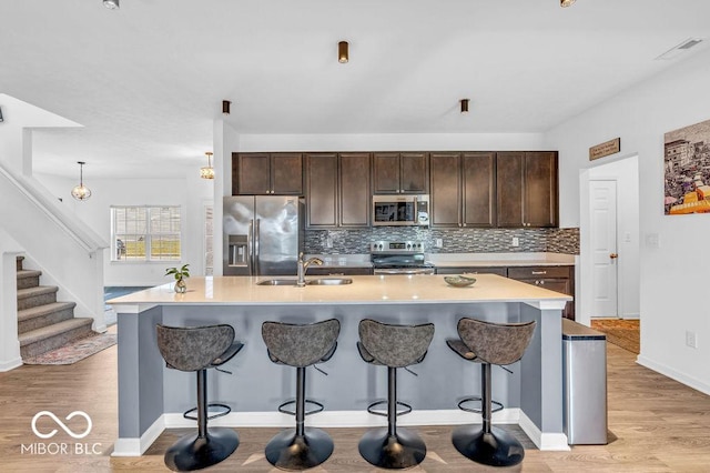 5256 Bramwell Ln, Whitestown, IN 46075 - kitchen featuring appliances with stainless steel finishes, a sink, dark brown cabinets, backsplash, and a breakfast bar