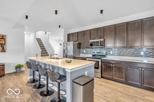 5256 Bramwell Ln, Whitestown, IN 46075 - kitchen featuring stainless steel appliances, light countertops, a sink, a breakfast bar, and light wood finished floors