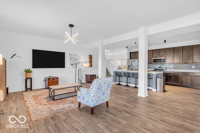 5256 Bramwell Ln, Whitestown, IN 46075 - living room featuring light wood-type flooring, stairway, baseboards, and a chandelier