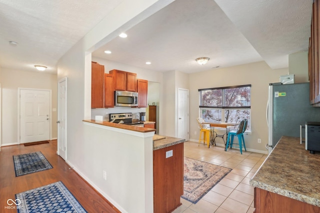 13063 E 131st St, Fishers, IN 46037 - kitchen featuring stainless steel appliances, brown cabinets, baseboards, recessed lighting, and a peninsula