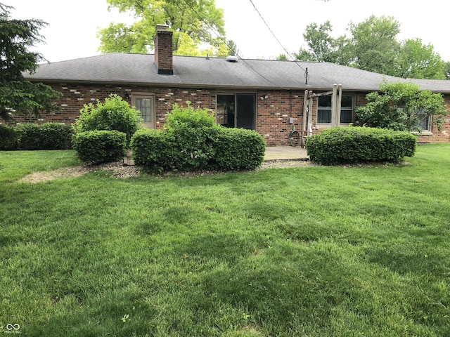 3619 31st St, Columbus, IN 47203 - back of property featuring a lawn, brick siding, a chimney, and roof with shingles