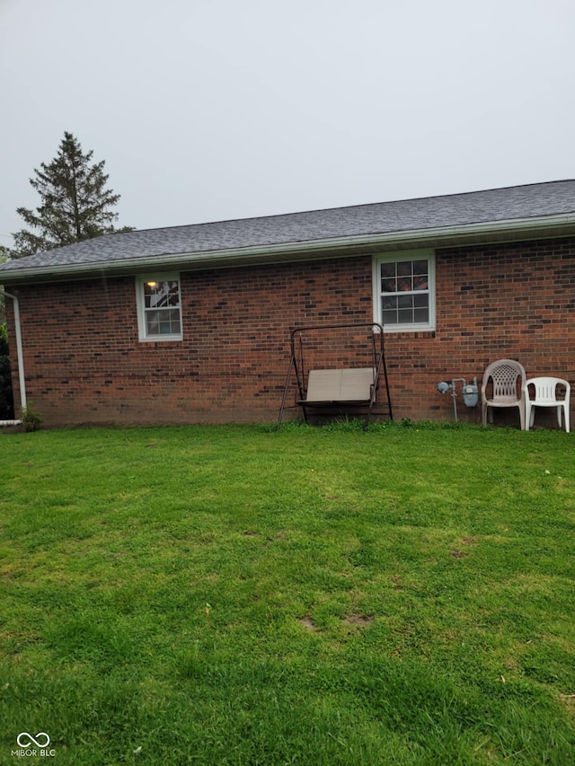 back of house featuring brick siding and a yard