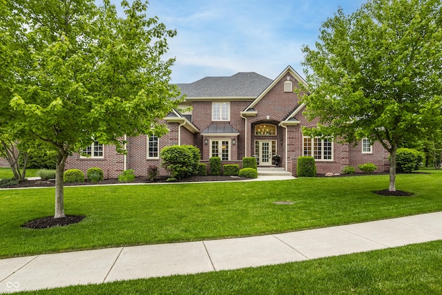 view of front of home featuring french doors, brick siding, and a front lawn