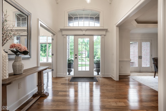 entryway featuring dark wood-style floors, ornamental molding, baseboards, a high ceiling, and french doors
