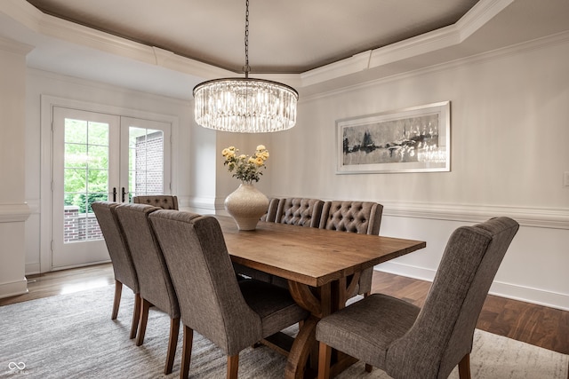 dining space with a tray ceiling, ornamental molding, a chandelier, wood finished floors, and french doors