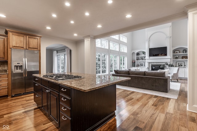 kitchen featuring stainless steel appliances, arched walkways, crown molding, stone countertops, and recessed lighting