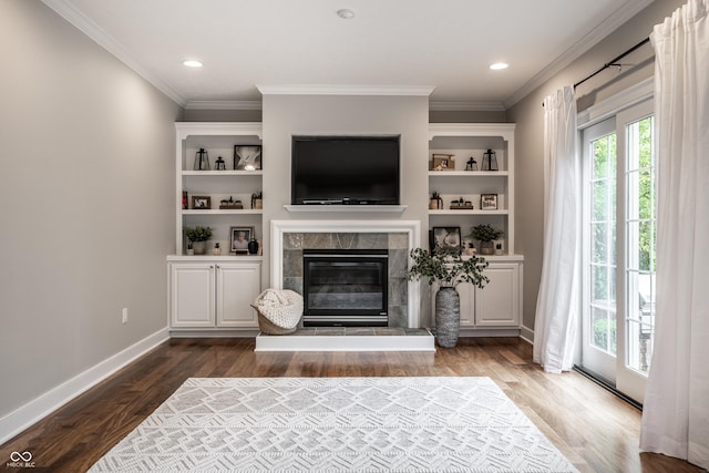 living area with wood finished floors, a tile fireplace, crown molding, baseboards, and recessed lighting