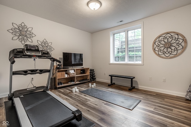 workout area with wood finished floors, baseboards, and a textured ceiling