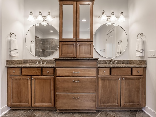 full bath with double vanity, tiled shower, baseboards, and ornamental molding
