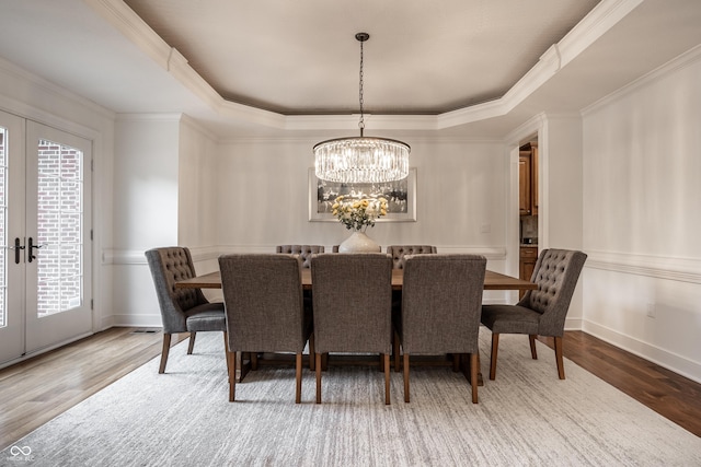 dining space featuring a tray ceiling, french doors, a chandelier, and ornamental molding