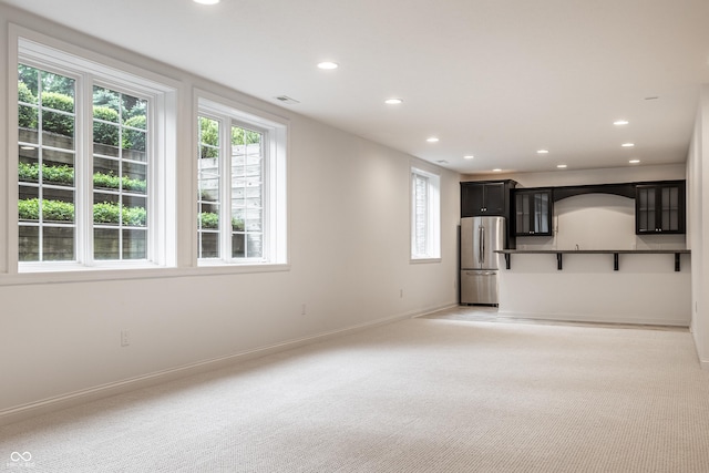unfurnished living room featuring healthy amount of natural light, recessed lighting, light carpet, and baseboards