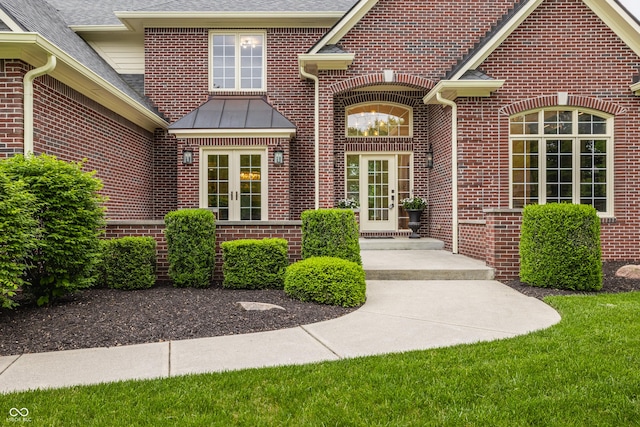 view of exterior entry featuring brick siding, roof with shingles, and french doors