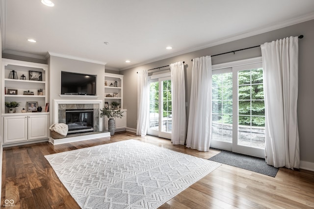 living room with ornamental molding, a tiled fireplace, wood finished floors, recessed lighting, and baseboards