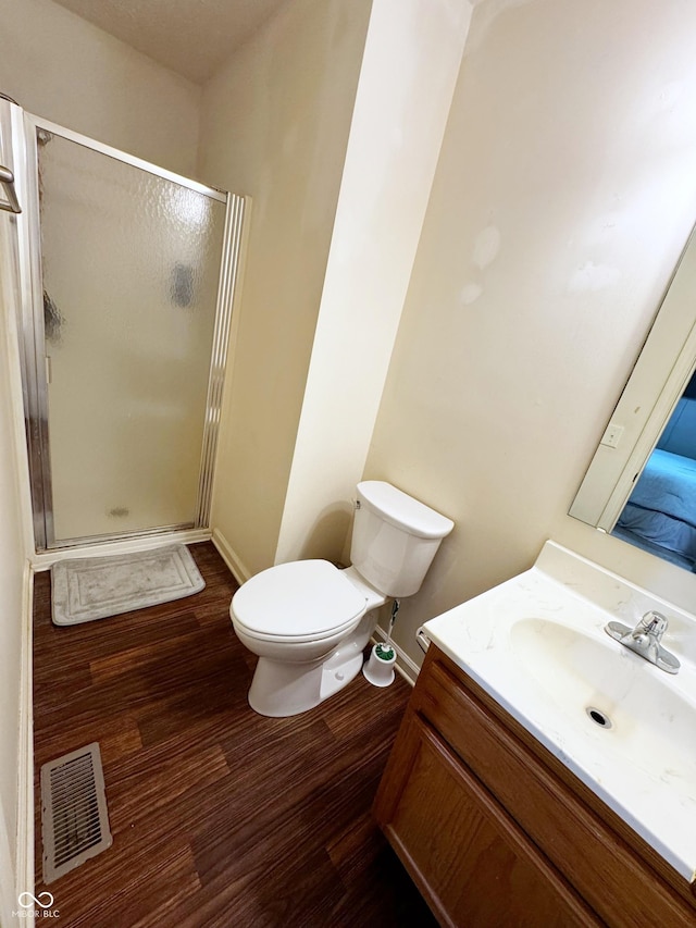 full bathroom featuring a shower stall, wood finished floors, vanity, toilet, and baseboards