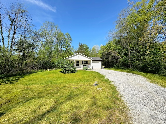 view of front facade with a front lawn, a porch, gravel driveway, and a garage