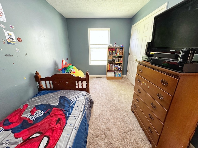 bedroom featuring light colored carpet, a textured ceiling, and baseboards