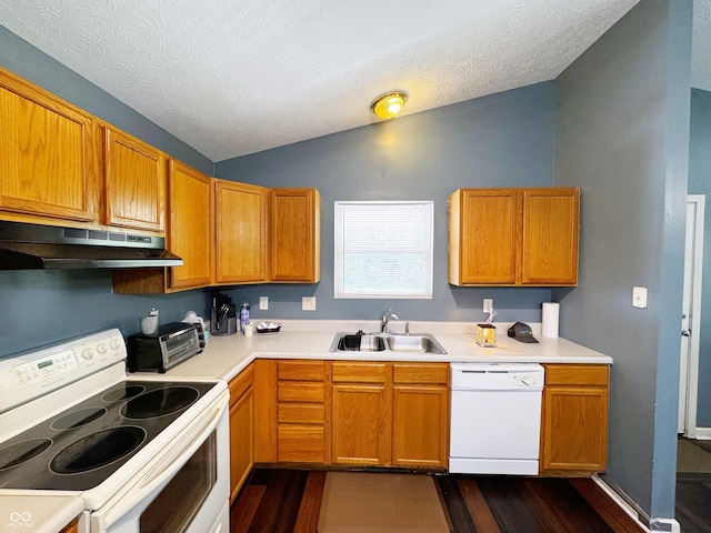 kitchen with white appliances, under cabinet range hood, a sink, lofted ceiling, and dark wood-style flooring
