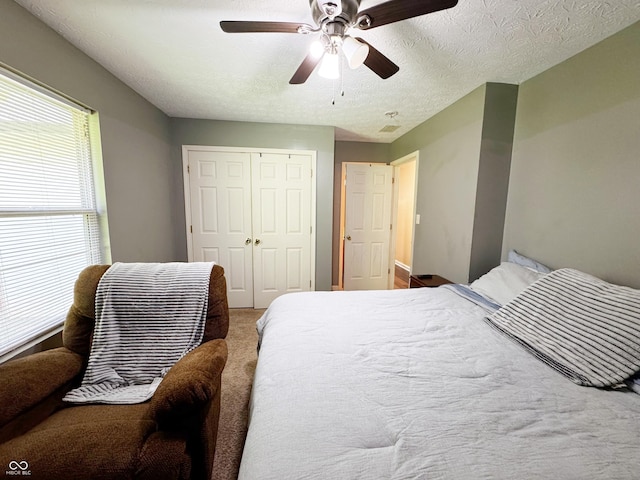 carpeted bedroom with a closet, a ceiling fan, and a textured ceiling