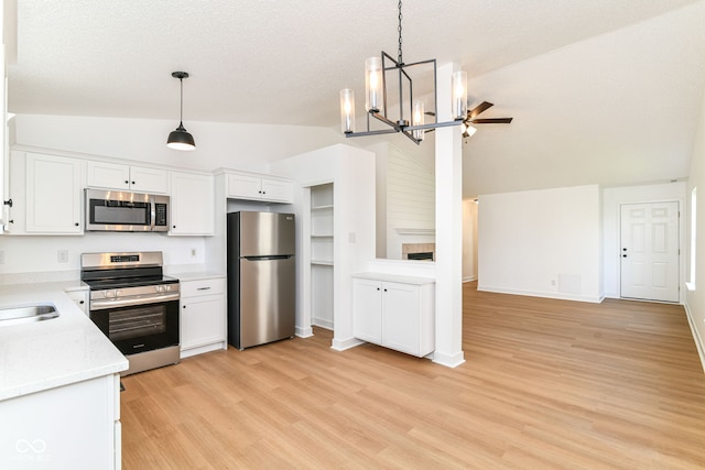 kitchen featuring stainless steel appliances, vaulted ceiling, a chandelier, white cabinets, and light wood-type flooring