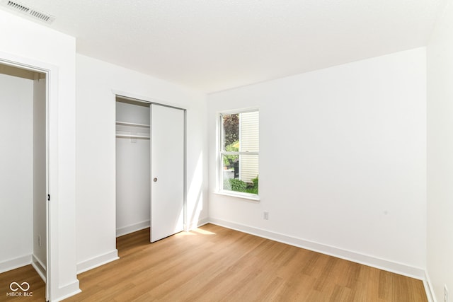 unfurnished bedroom featuring light wood finished floors, a closet, and baseboards