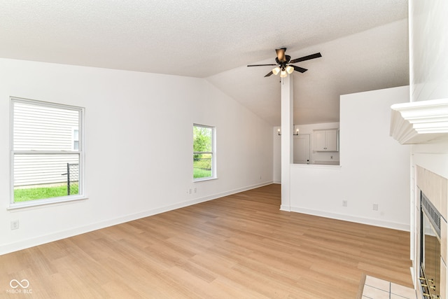 unfurnished living room featuring a fireplace, light wood finished floors, ceiling fan, vaulted ceiling, and baseboards
