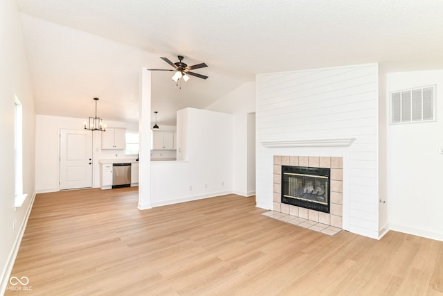 unfurnished living room featuring vaulted ceiling, a ceiling fan, light wood-style floors, a tiled fireplace, and baseboards