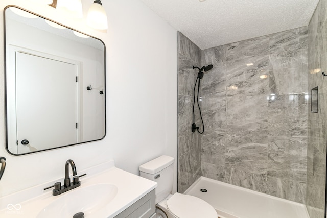 full bath with vanity, toilet, a stall shower, and a textured ceiling